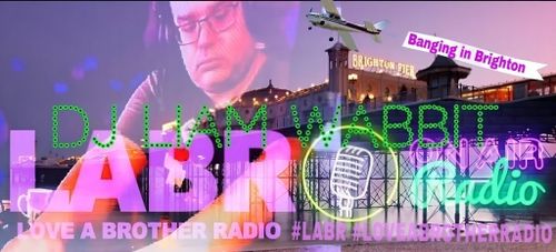 Background is a picture of Brighton Pier at sunset. with a plane flying over the pier with a banner following it that says Banging in Brighton in pink.  A picture of Liam, a white British Brother with glasses and headphones on. Leaning over his decks. Eyes and hands on the mixer. DJ Liam Wabbit in dots. LABR in pink. An old school microphone next to labr, with a yellow circle around it. The word, radio in Green. Love A Brother Radio right under it. Also in Pink.